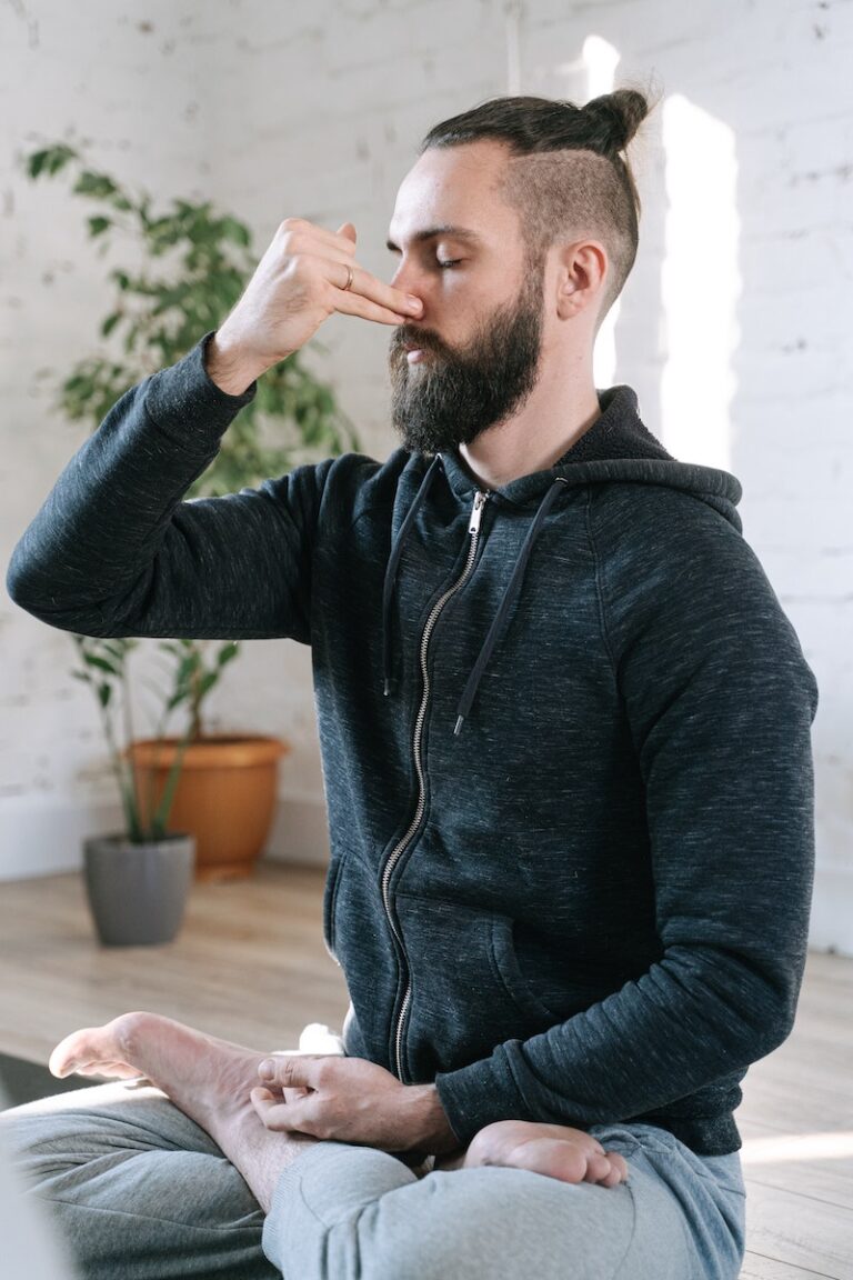 man with clothing on sitting down on floor performing a breath technique